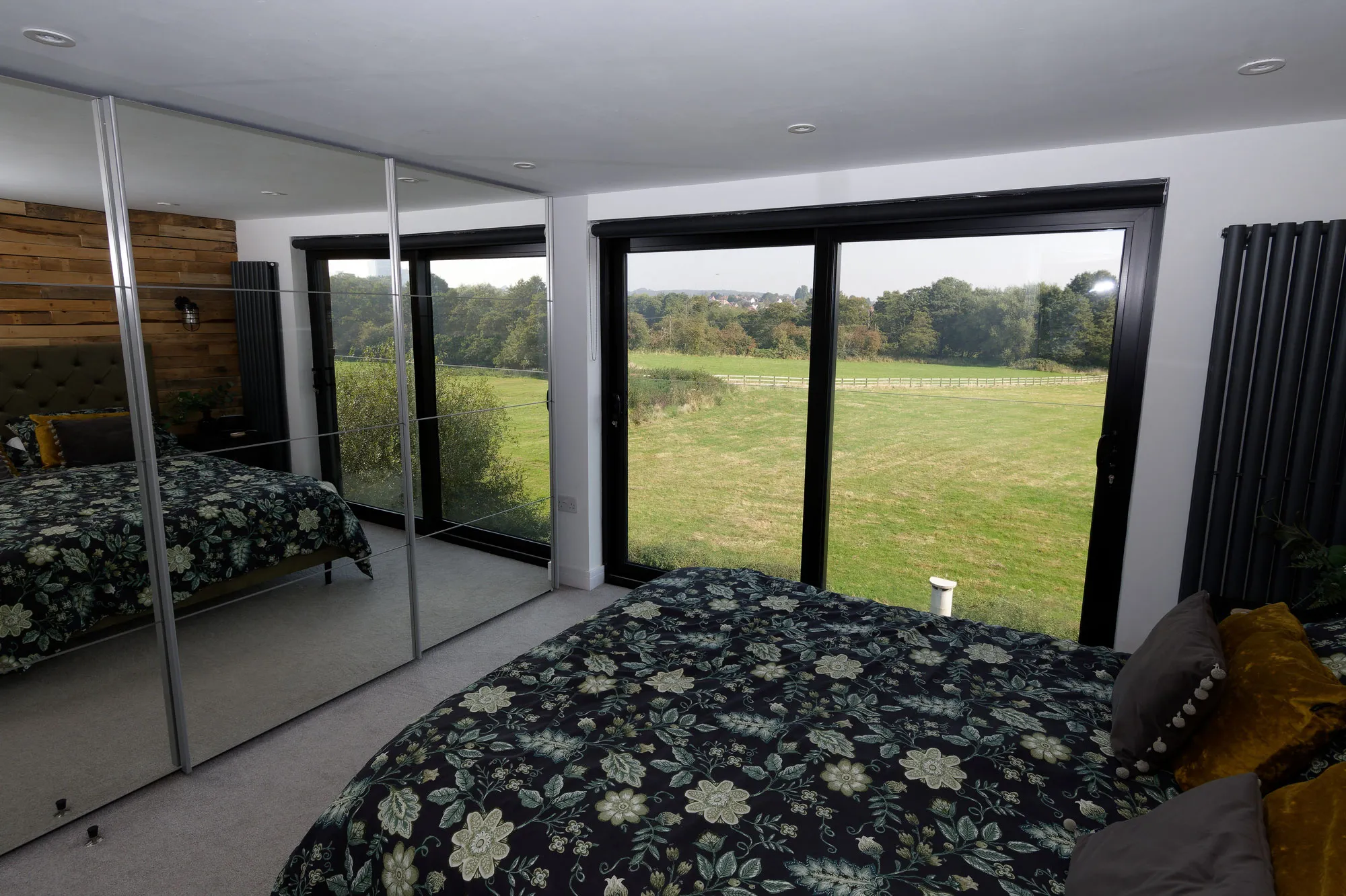 a bedroom with a large bed and a mirrored wall