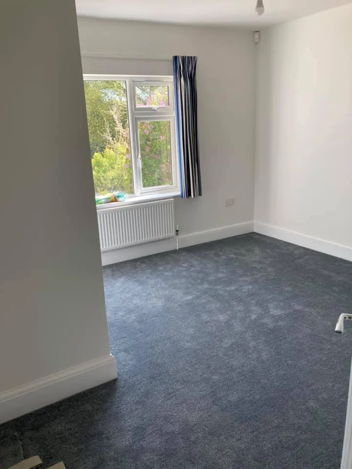 an empty room with a blue carpet and a window