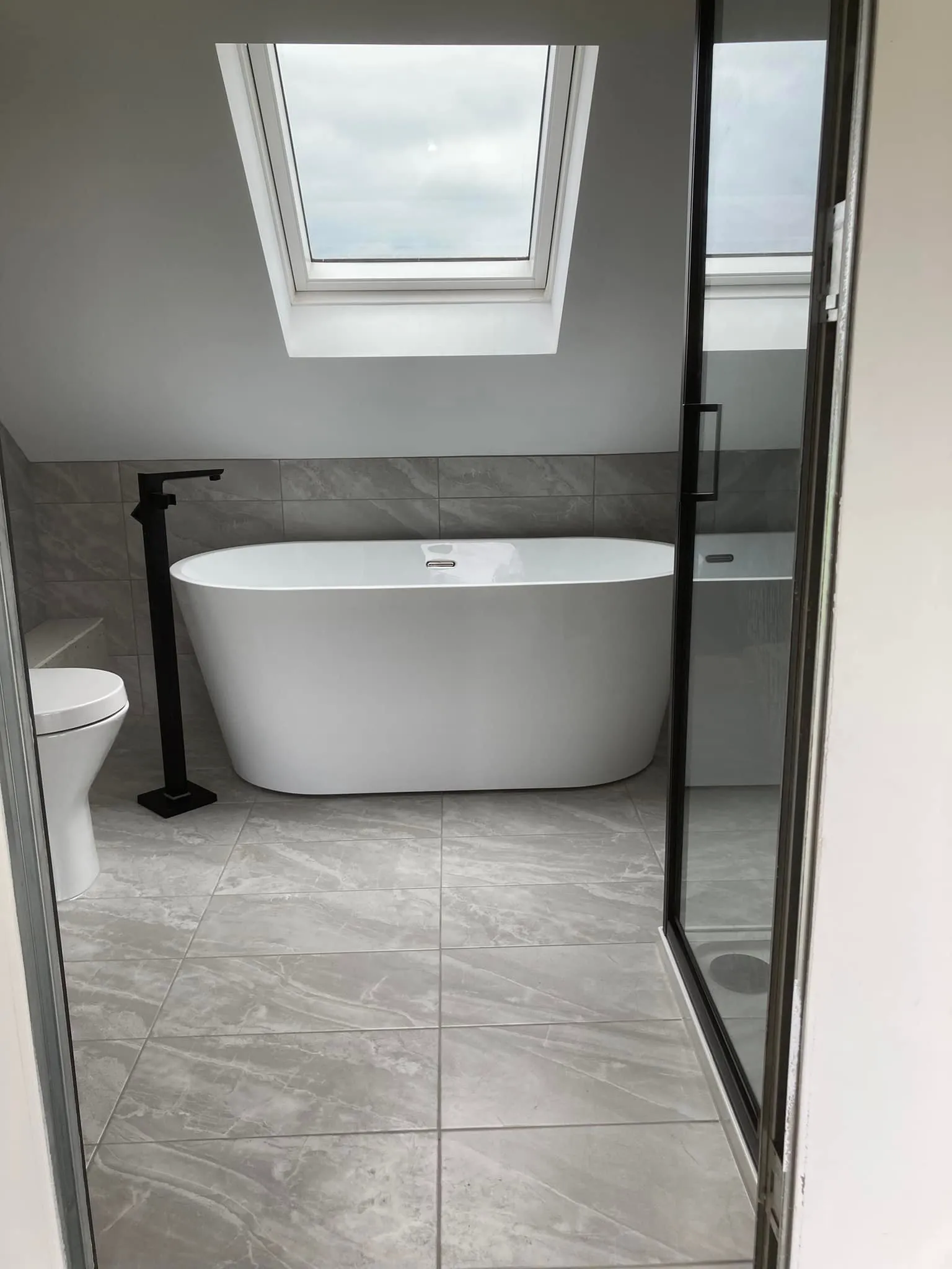 a white bath tub sitting under a window next to a toilet